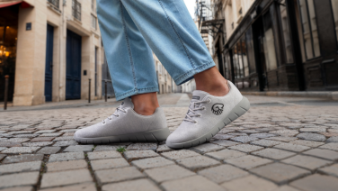 Detail: Feet in light grey Giesswein Merino Wool sneakers on historic cobblestones in a Mediterranean old town alleyway